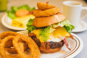 A bacon cheeseburger with onion rings served at a brightly lit American restaurant 