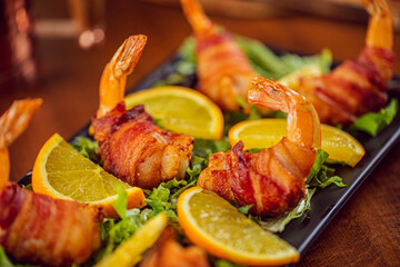 Mexican momias or bacon wrapped shrimp served with lemon on a bed of lettuce at a Mexican food restaurant 