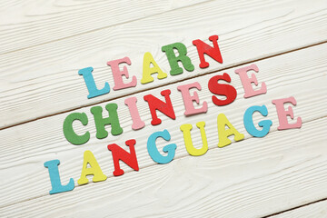 Text LEARN CHINESE LANGUAGE on white wooden background
