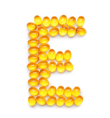 Fototapeta premium Vitamin E capsules in shape of letter on white background