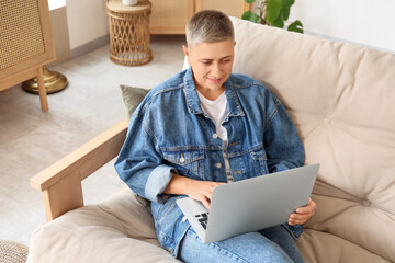 Young woman with short hair using laptop on sofa at home