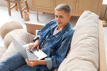 Young woman with short hair using laptop on sofa at home