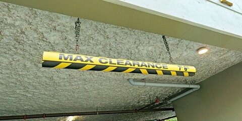 Yellow and black clearance bar indicating a maximum height of 7 feet 6 inches in a parking garage entrance.