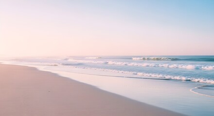 Soft pastel colored ocean waves gently washing onto a sandy beach at sunrise or sunset with a calm sea and sky