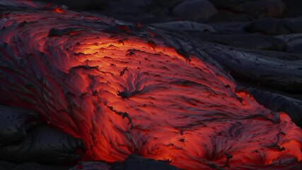 Molten lava flowing over volcanic rock with bright red colors