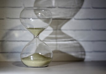 Hourglass as symbol of passing time concept photo shadow on the wall