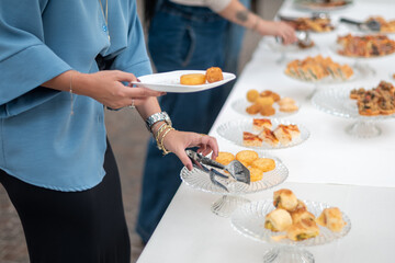 Guests select delicious food from an elegant buffet table during a private event showcasing a variety of appetizers and treats presented artfully on clear glass platters ideal for social gatherings