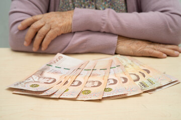 Retired Asian elderly woman counting coins money and worry about monthly expenses and treatment fee payment.