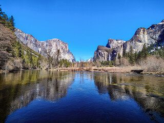 Scenic landscape view of Yosemite Valley with El Capitan and Cathedral Rocks reflected in calm water. Yosemite National Park, California