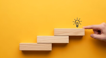 Hand touching wooden blocks leading to a light bulb on a yellow background
