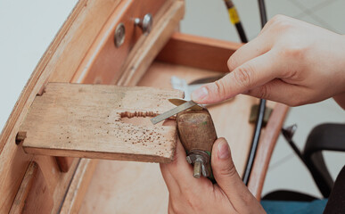 Jeweler artisan hands filing metal with hand file on wooden bench pin in jewelry workshop, handmade jewelry process, precision craftsmanship and traditional metalworking