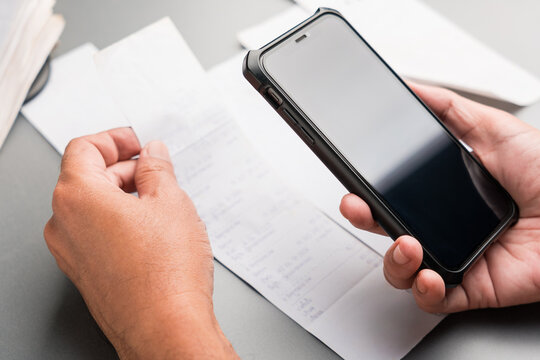 Hand using smartphone to scan and photograph receipts for budgeting, expense tracking, and tax deduction