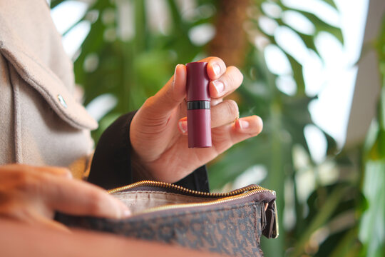 Holding a lipstick inside a stylish handbag for touch-ups