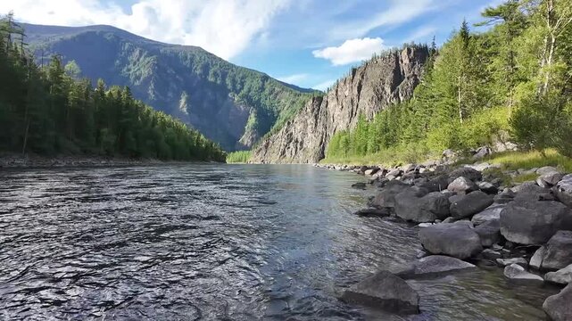 Static wide shot of a clear mountain river flowing between forested slopes and rocky cliffs &mdash; serene natural beauty perfect for cinematic backgrounds or travel documentaries.