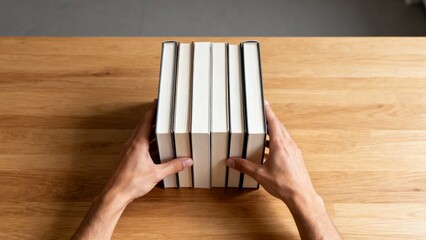 Adult Hands Organizing Books on Table