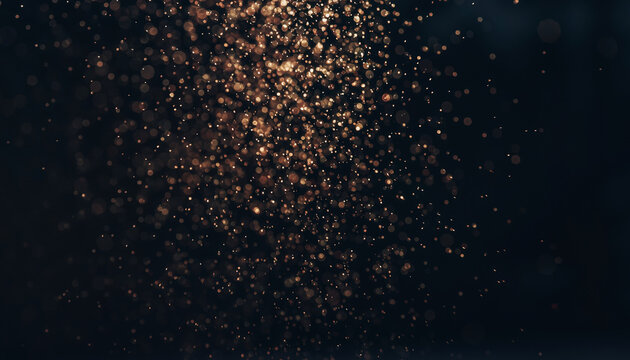 Abstract dark background with shimmering golden particles creating a magical and ethereal bokeh effect.