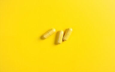 Close-up of yellow vitamin capsules on a yellow background. High quality