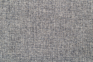 Coarse, tightly woven fabric in shades of grey and white, showcasing its distinct basketweave or tweed-like texture. A background for various design, including fashion, upholstery, or abstract themes.