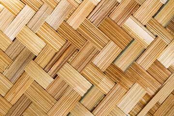 Close-up of a natural woven bamboo texture with a distinctive diagonal or herringbone pattern. The warm, earthy tones and visible grain of the bamboo strips create a rich decorative element.