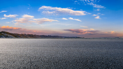 Empty asphalt road with distant mountain landscape and wind turbines under a beautiful sunset sky