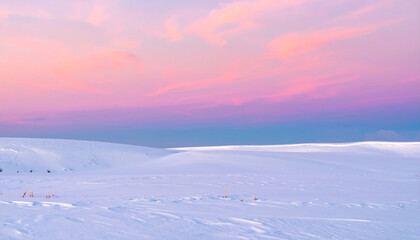 Hilly field covered with snow snowy winter rural landscape during sunset with colorful sky