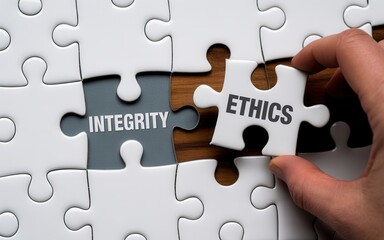 Fototapeta premium Hand placing the ethics puzzle piece into integrity puzzle