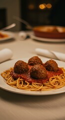 Savory plate of spaghetti topped with rich tomato sauce and four large meatballs rests upon a dining table