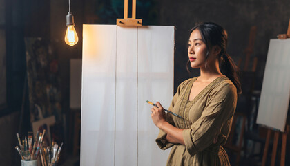 Artist with brush contemplates blank canvas in studio.