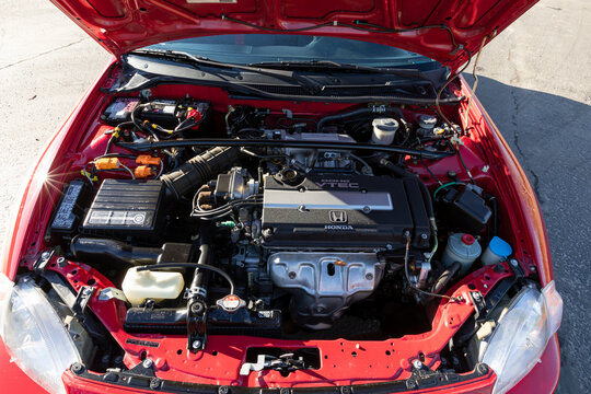 Portland, OR, USA - Jan 14, 2021 - engine bay of 1995 red Honda Civic Del Sol DOHC VTEC showing motor components wiring hoses and parts in bright daylight