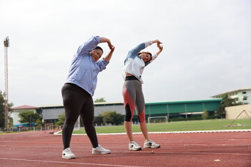 Two slim and plus size woman with sport jacket together stretch warm-up exercise on an outdoor running track, wellness and healthy lifestyle