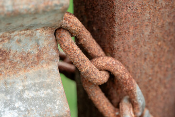 Macro close-up of a thick, heavily corroded iron chain, covered in orange rust.