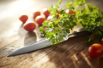 Fresh cherry tomatoes and parsley with a knife on a rustic wooden table with soft natural light
