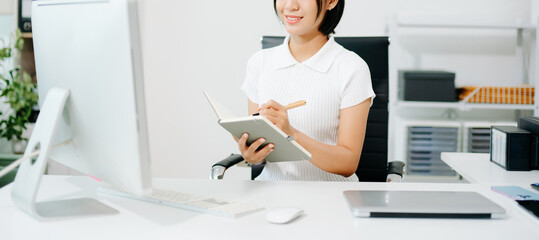 A focused office woman writing notes and working on paperwork at her desk, representing productivity, organization, business tasks,