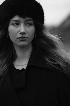 Woman fashion portrait in a black winter fur hat. Vind in hair	