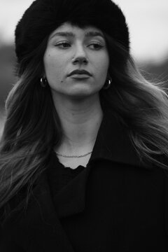 Woman fashion portrait in a black winter fur hat. Vind in hair	