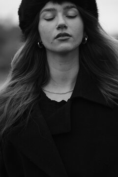 Woman fashion portrait in a black winter fur hat. Vind in hair	