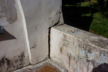 Grungy corner of an abandoned manor wall, showcasing aged peeling paint and deep structural cracks. Texture of urban decay, forgotten history
