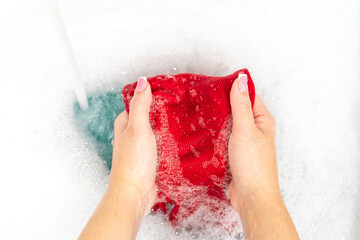 Female hands washing bright red shirt