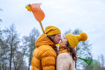 Midlife couple in cozy autumn attire, playfully raking leaves together in a serene outdoor setting, surrounded by colorful fall foliage and a sense of joy and togetherness