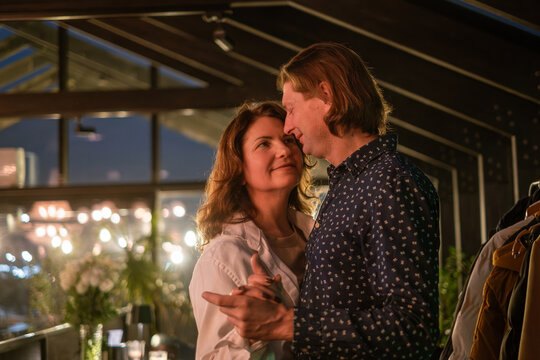 Middle-aged couple enjoying a romantic evening together in a cozy cafe, surrounded by warm lighting and intimate ambiance, capturing the essence of love and connection