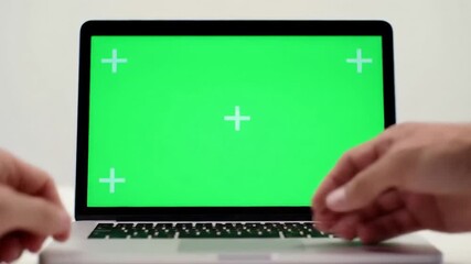 Two business people shaking hands over a laptop with a green screen symbolizing a successful online deal or partnership in a modern digital environment. - Powered by Adobe