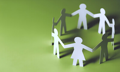 Teamwork makes the dream work with a circle of diverse paper people holding hands on vibrant green background, community and collaboration