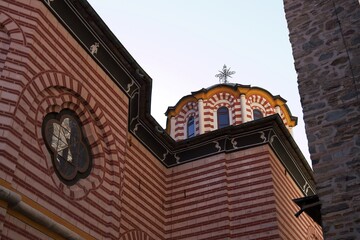 Close view of the honey-colored dome of the Rila Monastery chapel, showing the cross on top, the inscription “1870,” and the colorful arches and columns, Rila, Bulgaria, 01 Nov. 2025
