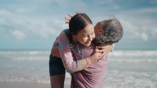 A young girl running to her senior grandmother for a loving hug on a sunny beach. Leisure enjoying the weekend concept
