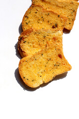Crispy garlic bread slices on white background.
