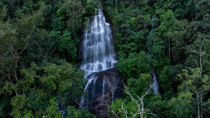 Aerial view of waterfall surrounded by lush jungle and rocks, Waterfall and forest green tree, Waterfall in deep jungle with forest tree.