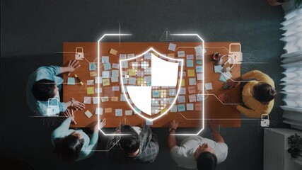 A diverse group of professionals collaborates on cybersecurity strategies around a table, showcasing a digital shield overlay that symbolizes data protection efforts. Raster