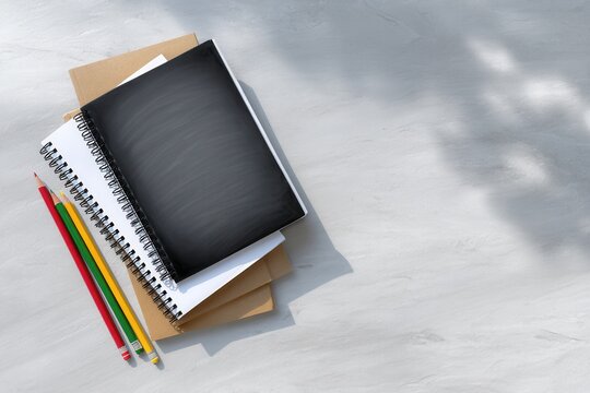 A collection of notebooks and colored pencils arranged on a light gray background, ideal for educational or creative themes.