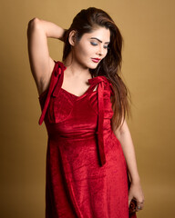 High-quality studio portrait of a stylish woman wearing a red velvet dress and posing confidently against a yellow backdrop. Ideal for themes of fashion, beauty, lifestyle, and elegance