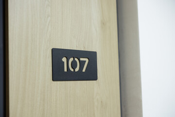 Sunlit hallway revealing room number 107 in an unfinished building with a modern touch